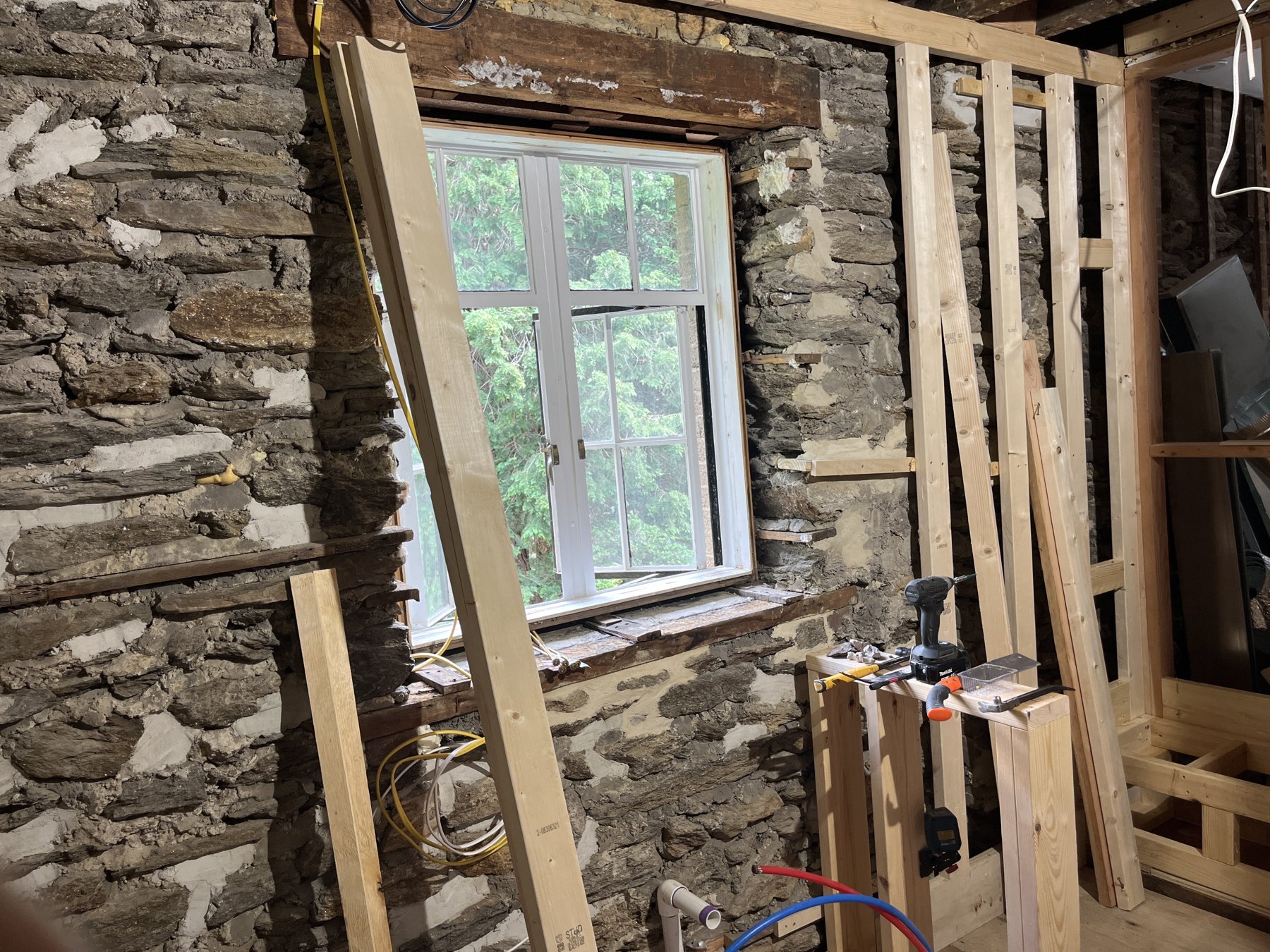 Retained stone wall and window beside new interior framing