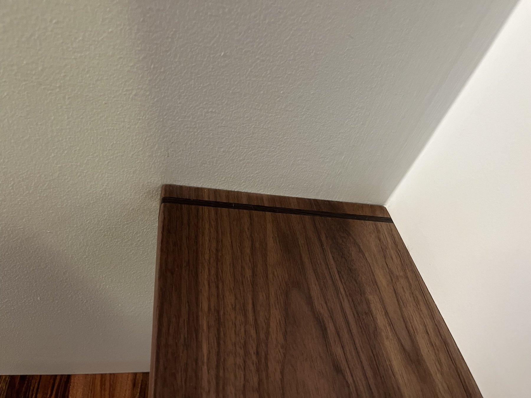 Shallow cantilevered walnut shelf with a wenge inlay near the fitted end