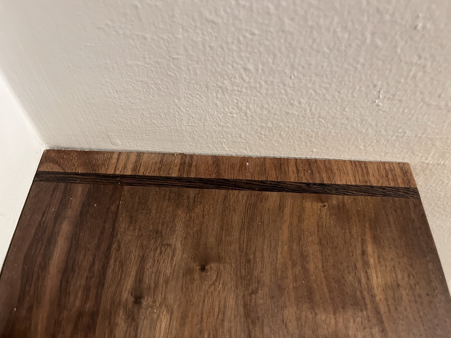 Dark wenge inlay crossing the end of a walnut shelf