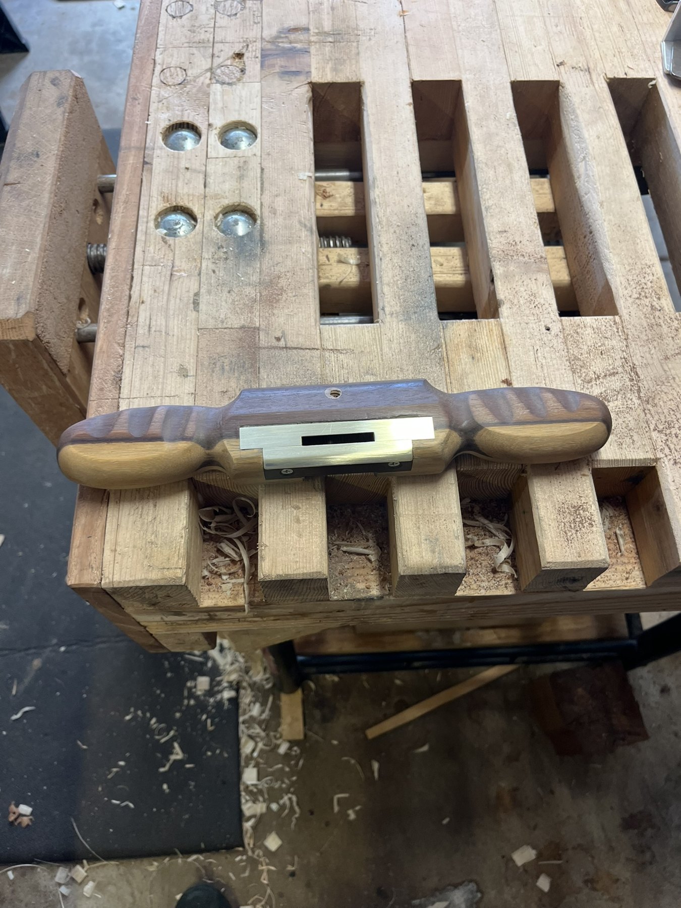 Underside of a handmade wooden spokeshave with an inset brass sole and cutter opening